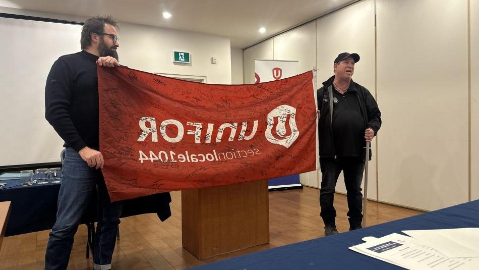 Two men holding a signed 十博官网在线 flag