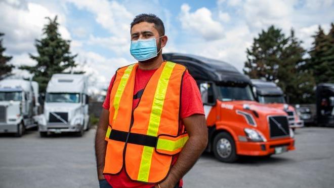Man in safety vest and face mask standing in front of a truck