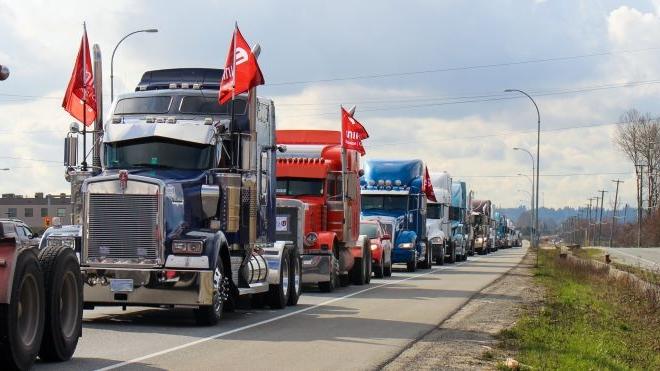 Long convoy of tractor trailer trucks, some with with 十博官网在线 flags