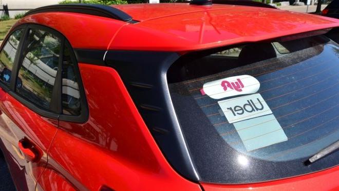 红色汽车的后窗上有Lyft和Uber的贴纸. 